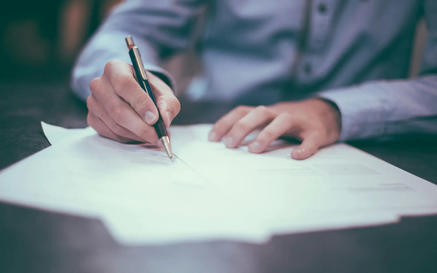 Mano firmando una escritura con lapicera